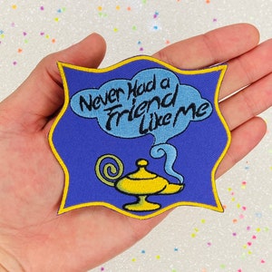 May include: A blue and yellow embroidered patch with a genie lamp and a speech bubble that says "Never had a friend like me".