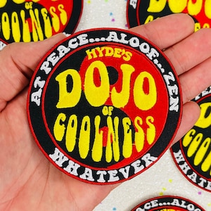 May include: A black and red circular embroidered patch with the text "Hyde's Dojo of Coolness Whatever" in yellow and white lettering. The patch features a yin yang symbol.