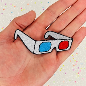 May include: White embroidered iron-on patch of 3D glasses with blue and red lenses.