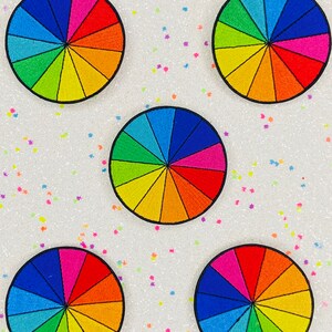 May include: Five colorful embroidered patches in the shape of a color wheel. Each patch has 12 sections of different colors, including red, orange, yellow, green, blue, and purple.