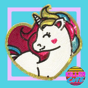 May include: A white unicorn with a pink, blue and yellow mane and tail, in a heart shape, made of sequins. The unicorn is smiling and has its eyes closed. The background is a light blue colour.