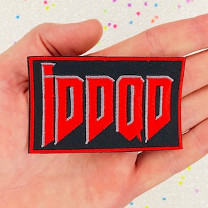 May include: Red and gray embroidered patch with the text "IDDQD" on a black background.
