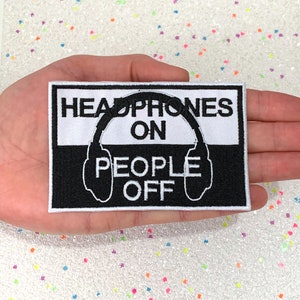 May include: Black and white embroidered patch with the text "Headphones On People Off" and a graphic of headphones.