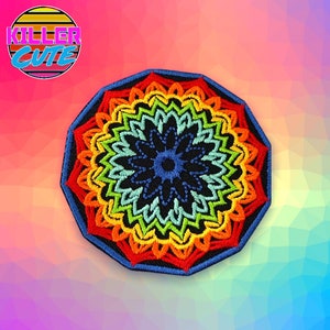 May include: Embroidered patch with a colorful mandala design. The patch features a black center with a blue floral pattern, surrounded by concentric rings of red, orange, yellow, green, and blue. The patch is outlined in blue and has the text "KILLER CUTE" in a retro font.
