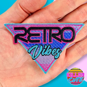 May include: An iron-on patch embroidered in pink, blue and purple with the text "RETRO Vibes" in a triangle shape.