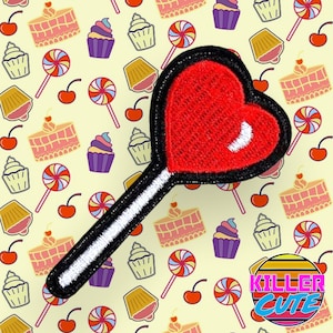 May include: Red heart-shaped lollipop with a white stick and black trim on a yellow background with a repeating pattern of cupcakes, cherries, and lollipops. The text "Killer Cute" is in the bottom right corner of the image.