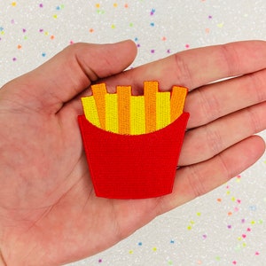 May include: Red and yellow embroidered iron-on patch of a cartoon chip container with chips sticking out of the top.