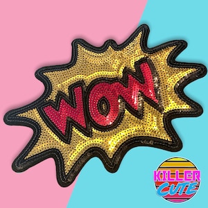 Pode incluir: Um remendo de lantejoulas douradas em forma de balão de fala de banda desenhada com a palavra "WOW" em lantejoulas vermelhas.