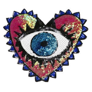 May include: A heart-shaped sequin patch featuring a large blue eye in the centre. The heart is outlined in blue and has a pink and yellow iridescent sequin design.