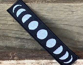 May include: Black fabric patch with a white embroidered design of the phases of the moon.