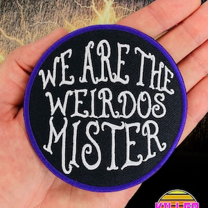 May include: A black and white embroidered patch with purple stitching. The patch is round and features the text "We are the weirdos mister".