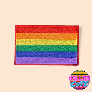 May include: A rainbow pride flag patch with red, orange, yellow, green, blue, and purple stripes. The patch is embroidered and has a red border.