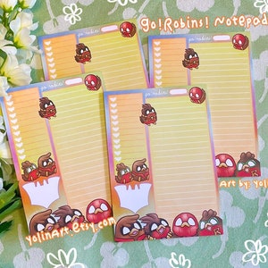 May include: Five yellow and orange notepads with lined paper and a colorful cartoon design of red robins. The notepads have the text "Go! Robins! Notepads" and "Art by: Yolin" printed on them.