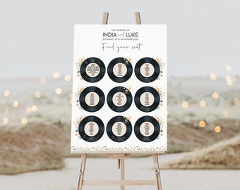 May include: A wedding seating chart with a vintage record theme. The chart features black vinyl records with white text listing guest names and table assignments. Each record is surrounded by a floral design with orange, blue, and white flowers. The text at the top reads "The Wedding of India and Luke, Saturday 25th November 2023, Find your seat."
