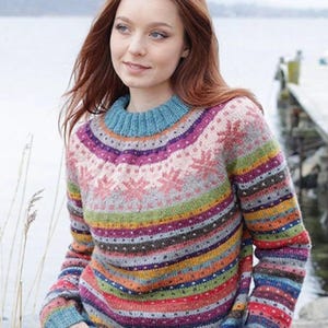 May include: A colorful sweater with a round neck and long sleeves. The sweater features horizontal stripes in various colors, including blue, purple, green, red, and yellow. The upper portion has a snowflake pattern. The sleeves and neckline are a solid blue.