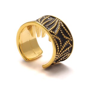 May include: Gold ear cuff with a black patterned design. The cuff is open and has a textured surface.