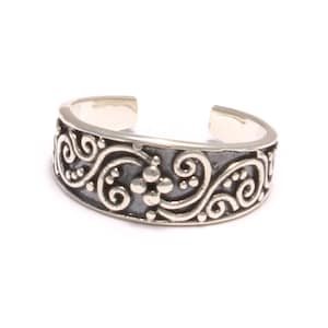 May include: Silver toe ring with a delicate, swirling design. The ring is adjustable and has a smooth finish.