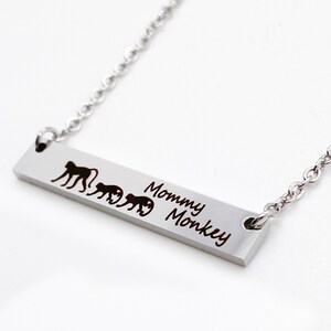 May include: Silver necklace with a bar pendant featuring a line of monkeys and the text "Mommy Monkey".