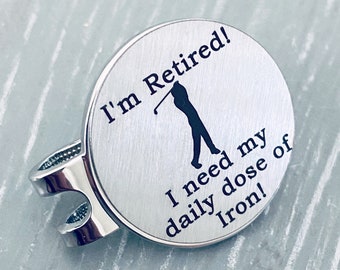 May include: Silver golf ball marker with a golfer silhouette and the text "I'm Retired! I need my daily dose of Iron!"