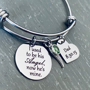 May include: Silver bangle bracelet with a charm that reads "I used to be his Angel, now he's mine." and a heart charm that reads "Dad 8.30.15".