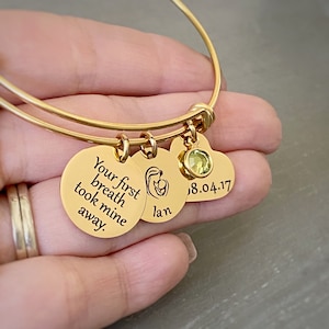 yellow gold new mom charm bracelet personalized with a round name charm Ian and a heart charm with babys date of birth 8.4.17 and an august peridot birthstone.