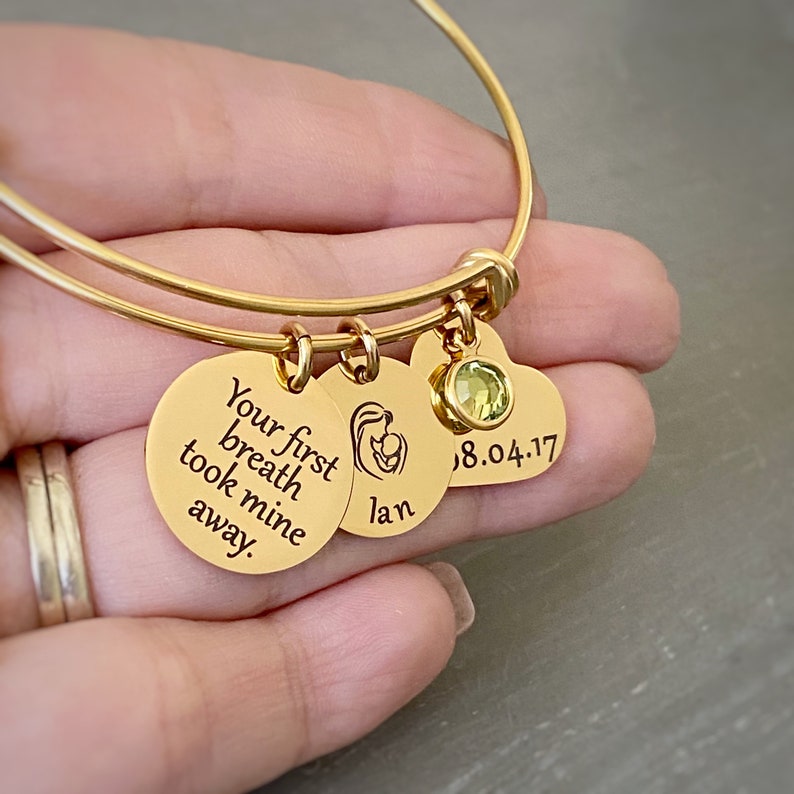 yellow gold new mom charm bracelet personalized with a round name charm Ian and a heart charm with babys date of birth 8.4.17 and an august peridot birthstone.