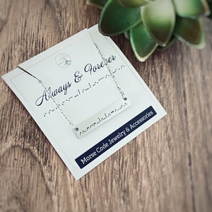 May include: A silver necklace with a bar pendant that says "Always & Forever" in Morse code. The necklace is displayed on a white card with the same message in Morse code and the words "Morse Code Jewelry & Accessories".