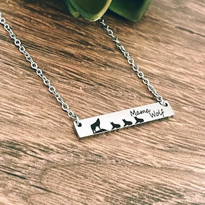 May include: A silver necklace with a bar pendant that says "Mama Wolf" and has five wolf silhouettes. The pendant is on a silver chain.