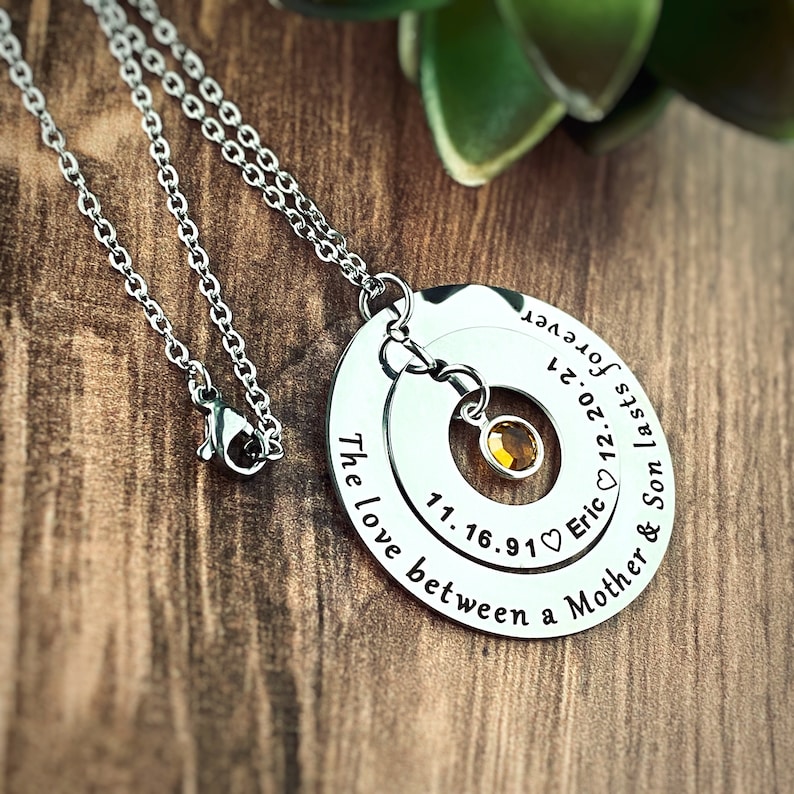Silver 2 pendant memorial necklace. Outer ring is engraved with the phrase The love between a Mother and Son lasts forever. The inside pendant is engraved with the sons birth date name and death date. birth stone dangles in the center.