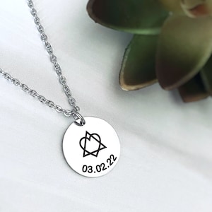 May include: A silver necklace with a round pendant featuring a stylized heart symbol and the date 03.02.22.