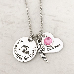 Puede incluir: Collar de plata con un dije redondo que dice "Too Beautiful for Earth" con un peque&ntilde;o &aacute;ngel y alas. El collar tambi&eacute;n tiene un dije en forma de coraz&oacute;n con el nombre "Catherine" y un cristal rosa.