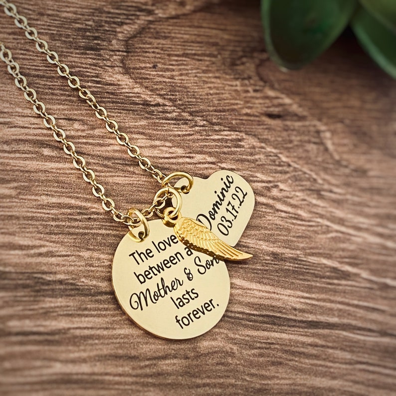 Puede incluir: Collar de oro con dos colgantes. El colgante m&aacute;s grande es redondo y dice "El amor entre una madre y su hijo dura para siempre". El colgante m&aacute;s peque&ntilde;o tiene forma de coraz&oacute;n y dice "Dominic 03.17.22".
