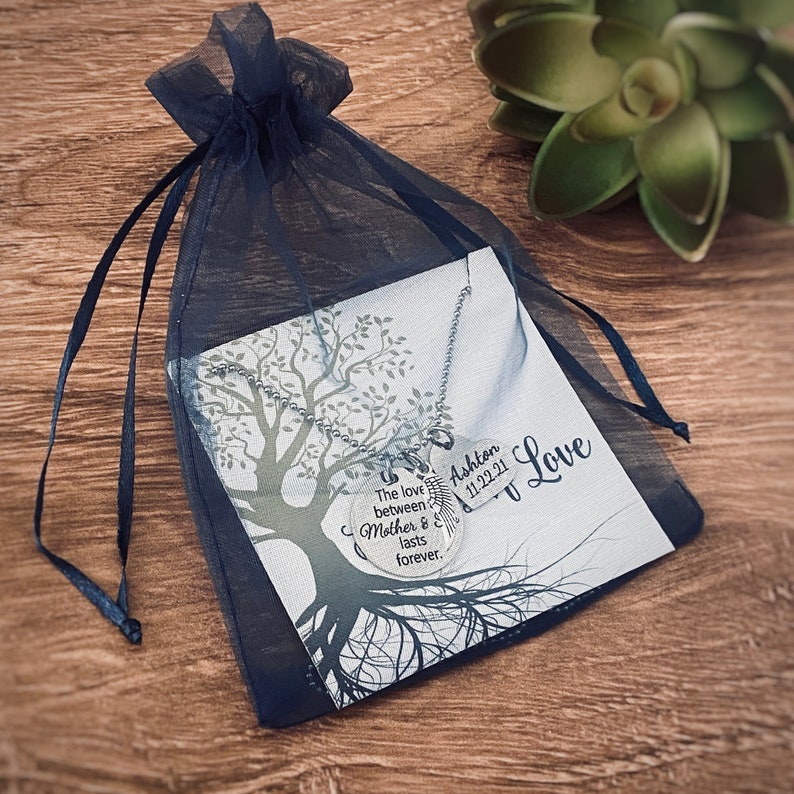 Puede incluir: Un collar de plata con un colgante redondo que dice "El amor entre madre e dura para siempre." El colgante tambi&eacute;n tiene un peque&ntilde;o dije de pluma y el nombre "Ashton 11.22.21" grabado en &eacute;l. El collar se muestra en una tarjeta blanca con un dise&ntilde;o de &aacute;rbol y las palabras "Mi amor".