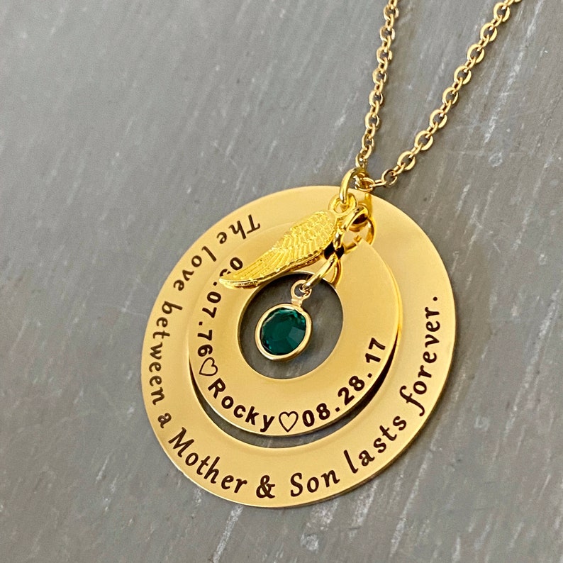 Yellow Gold Memorial necklace for mom who lost a son. outer ring engraved with sweet phrase inside ring engraved with sons information. The 2 large pendants are connected to a cable chain and dangle a angel wing charm and sons birthstone.