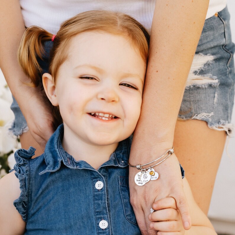 Picture of mom holding daughters hand wearing the Your first breath took mine away bangle charm bracelet