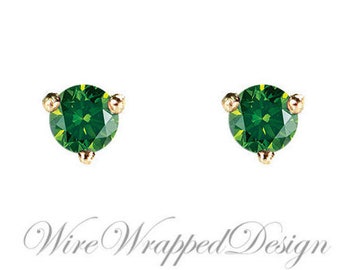 May include: A pair of gold stud earrings featuring green gemstones. The earrings are small and delicate, and the gemstones are round and faceted.