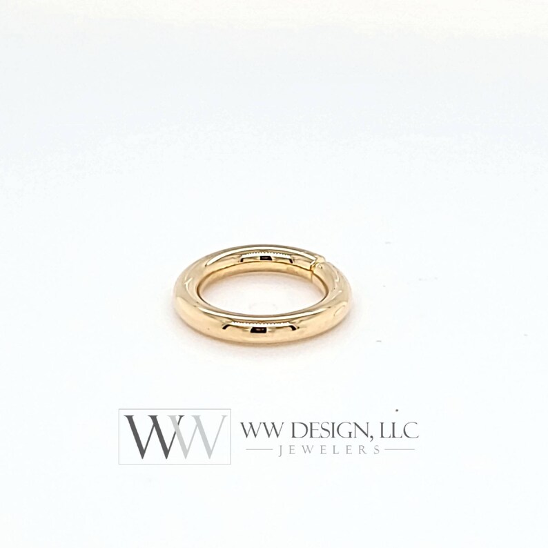 May include: A gold-colored ring with a smooth, rounded surface. The ring is open and appears to be made of metal.