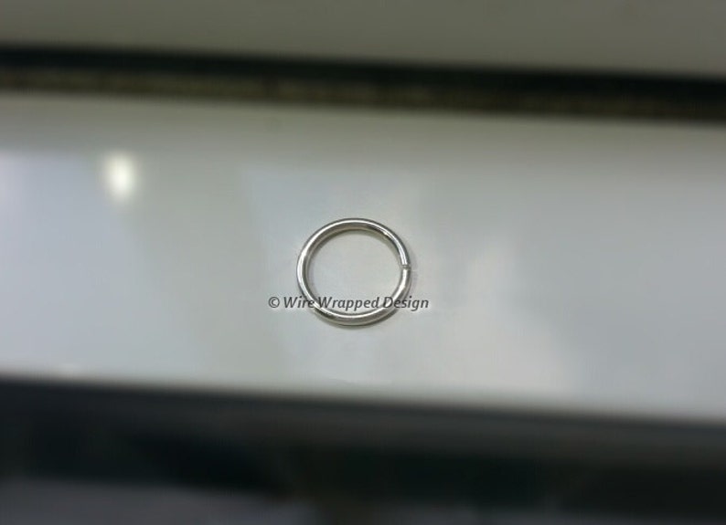 May include: A silver jump ring, a small metal ring used for connecting jewelry components.