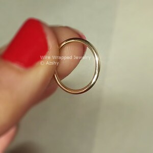 May include: A thin gold wire ring, held by a finger with red nail polish. The ring is simple and delicate, with a smooth, polished finish.  Wire Wrapped Jewelry &copy; Azzshy