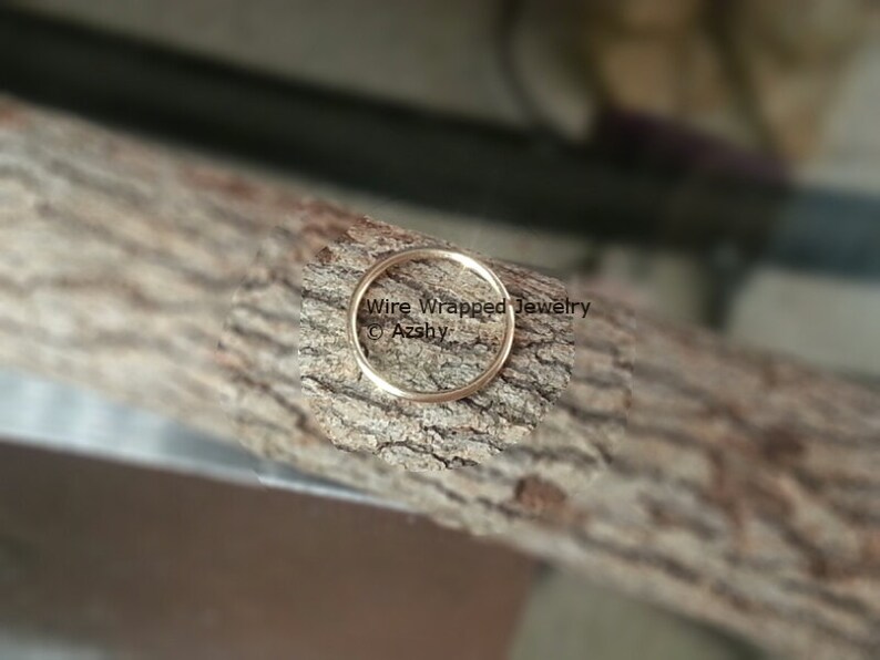 May include: A close-up of a gold wire wrapped ring on a piece of wood. The text "Wire Wrapped Jewelry &copy; Azshy" is visible in the image.