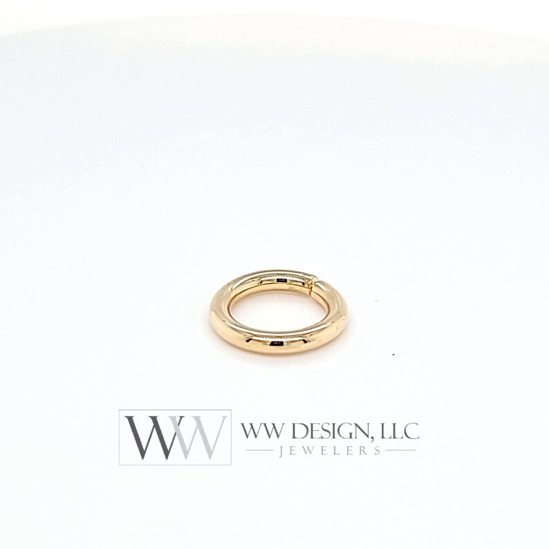 May include: Gold seamless ring with a smooth, polished finish. The ring is open and has a hinged closure.