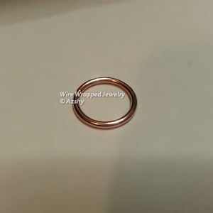 May include: A close-up of a rose gold wire wrapped ring. The ring is smooth and shiny. Wire Wrapped Jewelry &copy;Azshy