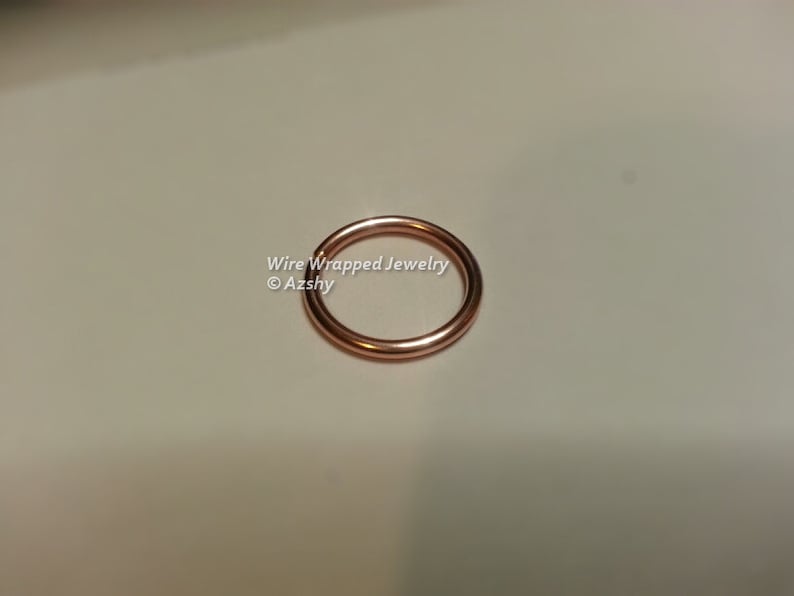 May include: A close-up of a rose gold wire wrapped ring. The ring is smooth and shiny. Wire Wrapped Jewelry &copy;Azshy