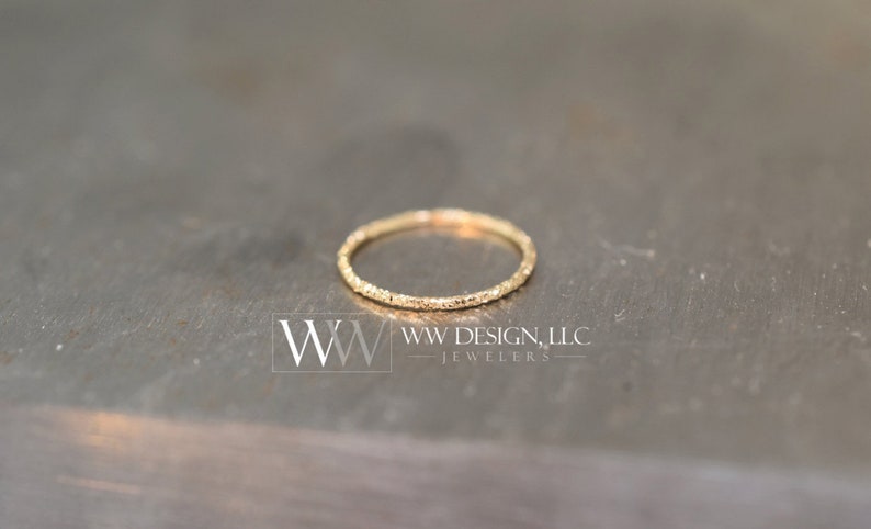 May include: A thin gold band ring with a textured surface.