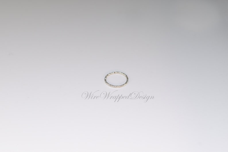 Pu&ograve; includere: Un anello d'argento con una fascia testurizzata. L'anello &egrave; su uno sfondo bianco.