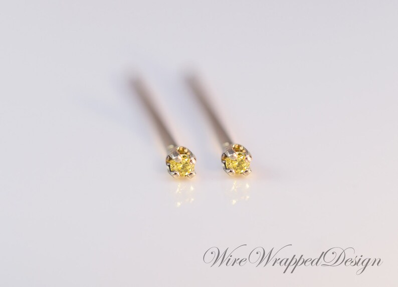 May include: A pair of gold stud earrings with small yellow gemstones.