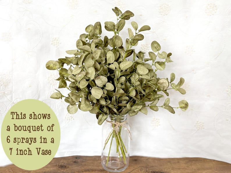 This shows a bouquet of faux eucalyptus in a glass jar. The arrangement contains 6 sprays in a 7 inch vase.