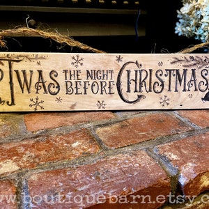 A horizontal wood sign. Twas the night before Christmas and reindeer are wood burned decoratively. The sign hangs with a piece of rope.