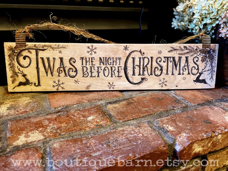 A horizontal wood sign. Twas the night before Christmas and reindeer are wood burned decoratively. The sign hangs with a piece of rope.