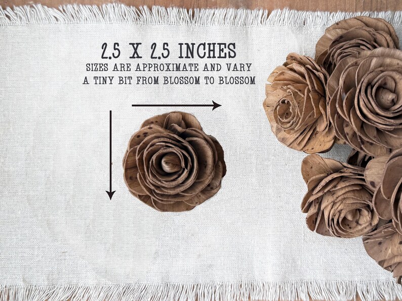 This shows a chocolate brown colored wood flower blossom sitting on a linen cloth. Arrows indicate that it is 2.5 by 2.5 inches.